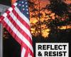 An American flag hangs on the left. Dark sillouettes of trees behind it are stark agains an orange sunset sky. In the bottom right corner are the words "Reflect & Resist."